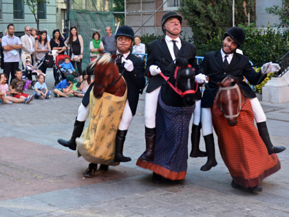 Les Goulus - Drei Männer in traditionellen Reiter-Outfits. Unten stecken die drei in Pferde-Figuren, die ihre eigenen Beine verdecken. Es sieht so aus, als würden sie reiten, obwohl sie laufen. Dabei schneiden sie Grimassen.